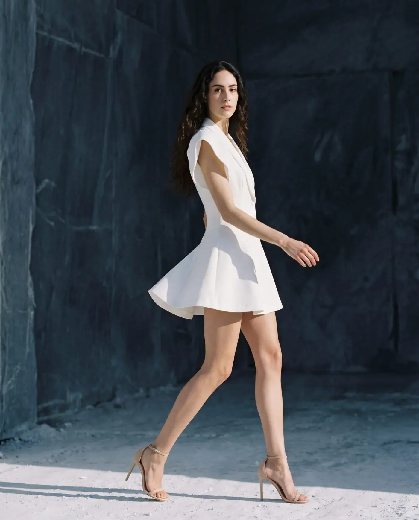 Lookbook without a shoot for a fashion brand: white mini dress on a model against dark stone